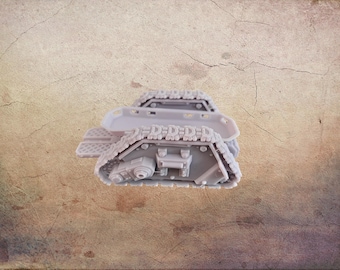 May include: A light gray miniature tank model with detailed track treads and a rectangular body. The model has a textured surface and is designed for hobbyists or collectors. The tank is a small scale model.