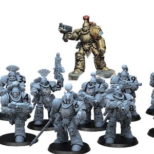 Könnte beinhalten: Eine Gruppe von 11 grauen Plastik-Miniaturfiguren von Weltraumkriegern, einige mit Waffen, die auf runden Sockeln stehen. Eine größere goldene Plastik-Miniaturfigur eines Weltraumkriegers steht in der Mitte.