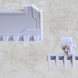 Può includere: Un set di due pezzi di modello in plastica bianca per un veicolo di wargaming in miniatura. Il primo pezzo è un grande pannello rettangolare con una superficie testurizzata e una serie di piccoli dettagli in rilievo. Il secondo pezzo è un pezzo rettangolare più piccolo con una serie di denti su un lato e due bracci articolati in rilievo sull'altro.