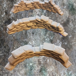 Puede incluir: Tres elementos arquitectónicos beige y curvos con un diseño en capas. Cada pieza tiene una superficie texturizada, que se asemeja a piedras o bloques apilados. Las piezas están dispuestas verticalmente sobre un fondo moteado.