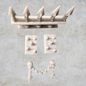 Könnte beinhalten: Ein Set aus Miniatur-Dungeon-Mauerteilen aus Kunststoff für Tabletop-Spiele. Das Set enthält eine Mauer mit Spikes, zwei Mauerabschnitte mit Spikes, eine Kette mit zwei Schädeln und einen Spike.