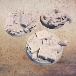 Könnte beinhalten: Drei graue Miniatur-Geländebasen für Tabletop-Spiele. Eine Basis zeigt einen Schädel, eine andere eine Sammlung von Kanistern und eine Kiste, und die dritte hat eine ähnliche Anordnung mit zusätzlichen Details.