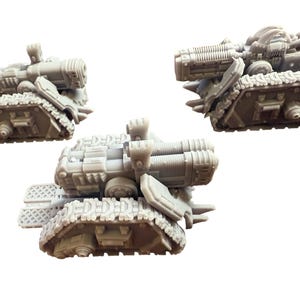 Puede incluir: Tres tanques en miniatura de plástico gris con cañones. Los tanques tienen orugas y ruedas detalladas.