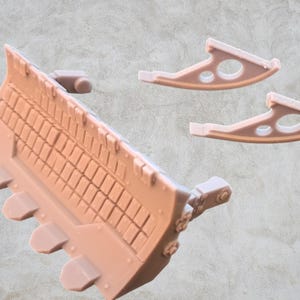 May include: A set of three plastic model parts for a vehicle. The main part is a large, detailed, light brown, rectangular piece with a series of small, rectangular holes. Two smaller, light brown, curved pieces with holes are also included.