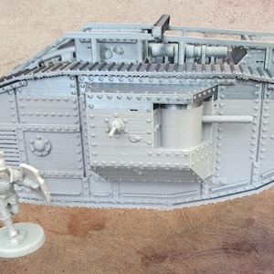 Può includere: Un modellino in scala grigio chiaro non dipinto di un carro armato Mark IV della Prima Guerra Mondiale con forma romboidale, corazzatura rivettata e sponson laterali con un cannone sporgente. Una piccola miniatura di soldato non dipinta è presente.