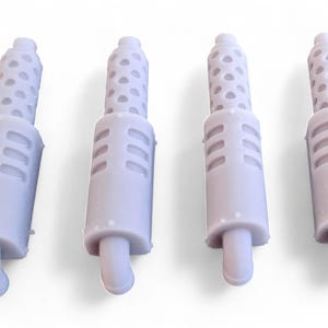 Può includere: Quattro kit di modelli di tubi di scarico in plastica bianca. Ogni tubo ha una superficie testurizzata e un'estremità arrotondata.