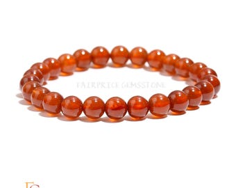 May include: A bracelet made of round, polished, orange-brown gemstones. The beads are strung together on an elastic band. The image includes the text "FAIRPRICE GEMSSTONE" and a logo.