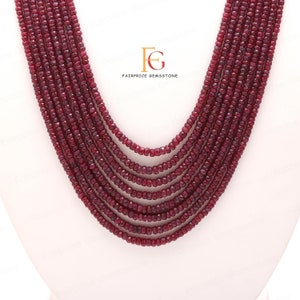 May include: A multi-strand necklace made of deep red ruby beads. The beads are faceted and have a slightly irregular shape. The necklace is approximately 18 inches long and is perfect for adding a touch of elegance to any outfit.