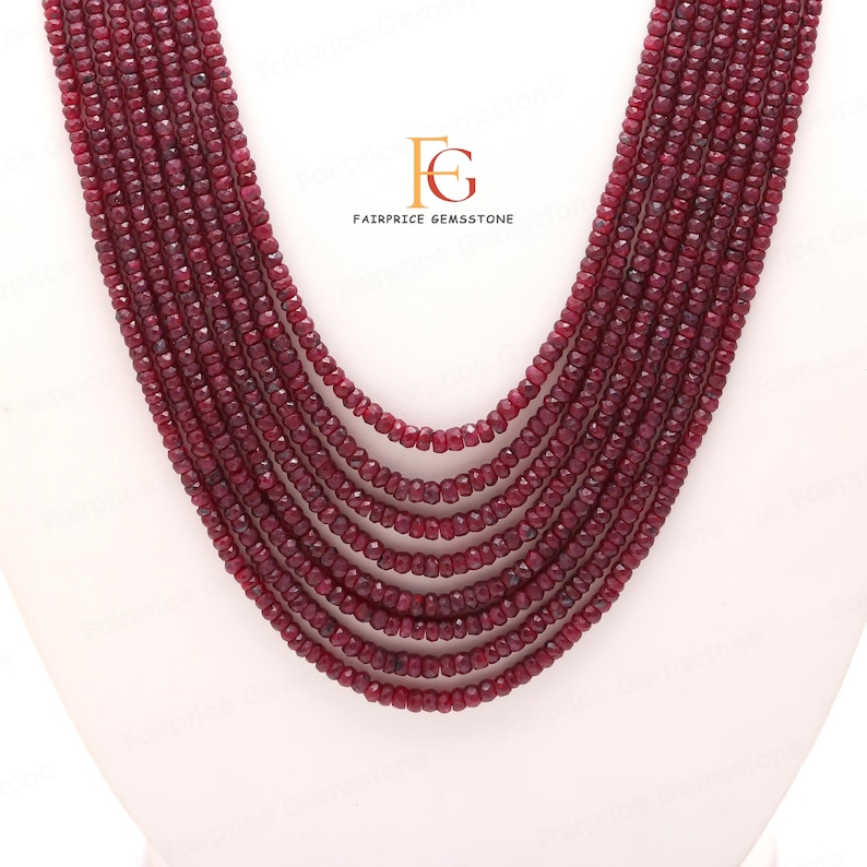 May include: A multi-strand necklace made of deep red ruby beads. The beads are faceted and have a slightly irregular shape. The necklace is approximately 18 inches long and is perfect for adding a touch of elegance to any outfit.