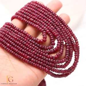 May include: A strand of deep red ruby beads, faceted and round, strung together on a white background. The beads are approximately 3mm in diameter and have a smooth, polished finish.