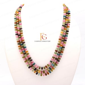 May include: A multi-strand necklace made of round, multi-coloured gemstones. The necklace is made of four strands of beads, each strand featuring a different colour combination. The beads are a mix of pink, green, blue, and yellow.