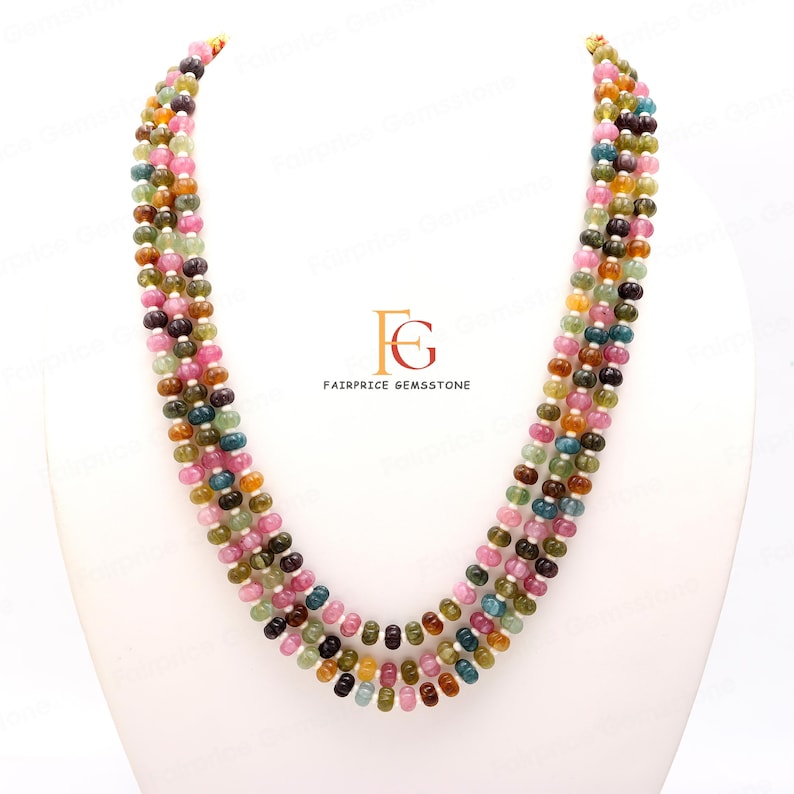 May include: A multi-strand necklace made of round, multi-coloured gemstones. The necklace is made of four strands of beads, each strand featuring a different colour combination. The beads are a mix of pink, green, blue, and yellow.
