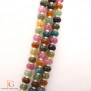May include: A strand of multi-coloured gemstone beads. The beads are round and have a faceted, pumpkin-like texture. The colours include pink, green, blue, brown, and yellow.