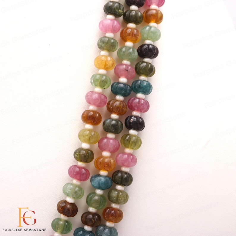 May include: A strand of multi-coloured gemstone beads. The beads are round and have a faceted, pumpkin-like texture. The colours include pink, green, blue, brown, and yellow.