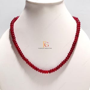 Puede incluir: Un collar de cuentas de piedras preciosas rojas. El collar está hecho de pequeñas cuentas redondas que están enhebradas en un cordón delgado. El collar mide aproximadamente 45 cm de largo.