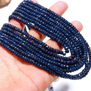 Op de afbeelding: Een streng donkerblauwe facetgeslepen edelsteen kralen. De kralen zijn klein en uniform in grootte, wat een gladde en elegante uitstraling creëert.