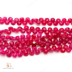 Op de afbeelding: Een streng helder roze facetgeslepen edelsteen kralen. De kralen zijn rond en hebben een licht onregelmatige vorm. De kralen zijn geregen op een doorzichtige draad.
