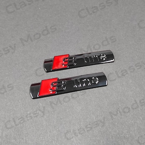 May include: Two black and red "S line" emblems. The emblems are made of metal and have a glossy finish.