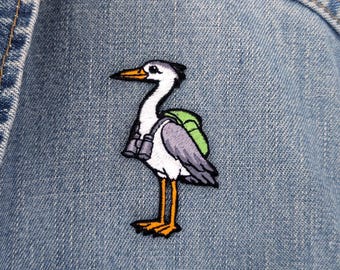 Aufnäher mit Reihermotiv | Gesticktes Vogelmotiv mit Fernglas und Rucksack, 60 mm