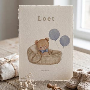 May include: A rectangular card with deckled edges featuring a watercolour illustration of a brown teddy bear wearing a blue bow tie inside a woven basket. Two blue balloons float above the bear. The text Loet and 11-06-2026 are printed on the card.