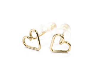 Puede incluir: Un par de pendientes de botón de corazón de oro. Los pendientes están hechos de un alambre fino y tienen un diseño simple y minimalista.