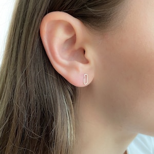 May include: A close-up of a person's ear with a small, oval-shaped silver earring.