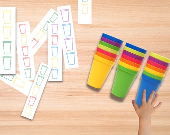 May include: A set of colorful plastic cups stacked in a rainbow pattern. The cups are arranged in three stacks, with each stack containing a different color. The cups are on a wooden surface.