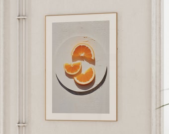 May include: A framed print of a still life featuring three orange slices on a white plate. The orange slices are arranged in a triangular shape and are illuminated by a warm light.