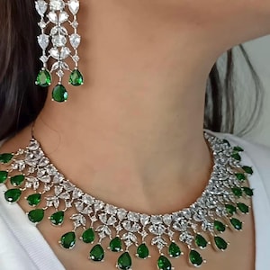 May include: A silver necklace with a white stone design and green teardrop-shaped stones hanging from the bottom. The necklace is paired with matching earrings. The text "LG 660" is visible in the bottom right corner of the image.