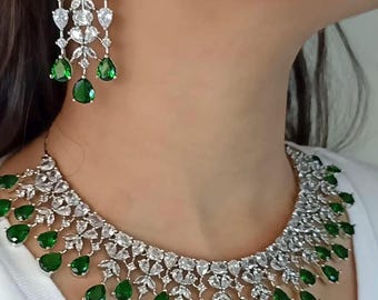 May include: A silver necklace with a white stone design and green teardrop-shaped stones hanging from the bottom. The necklace is paired with matching earrings. The text "LG 660" is visible in the bottom right corner of the image.