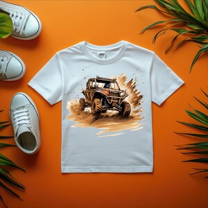 May include: White t-shirt with a graphic of a brown and black off-road vehicle driving through mud.