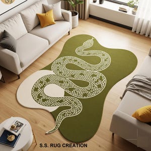 Peut inclure: Tapis vert et blanc cassé avec un motif de serpent. Le tapis a une forme organique avec un fond vert et un motif de serpent blanc. Le texte "S.S. RUG CREATION" est en bas.