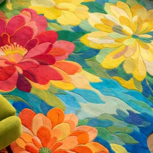 May include: A vibrant, floral-patterned rug featuring large, stylized flowers in shades of red, orange, yellow, and blue. The rug's design incorporates green leaves and a flowing, water-like pattern, creating a colorful and textured surface.
