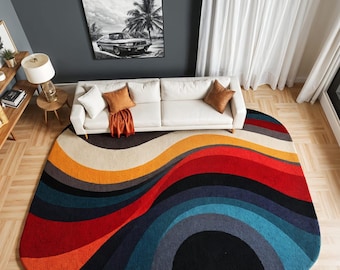 May include: A colorful area rug with a wavy design. The rug features a vibrant array of colors, including orange, red, blue, and black. The rug is placed in a living room setting, with a white sofa and artwork visible in the background. The text "S.S. RUG CREATION" is at the bottom.