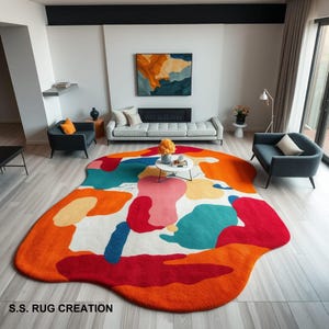 May include: A colourful abstract area rug with a white background and large, irregular shapes in shades of orange, red, pink, blue, and green. The rug has a unique, free-flowing design and is perfect for adding a touch of modern art to any room.