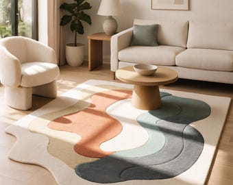Könnte beinhalten: Ein rechteckiger Teppich mit unregelmäßigem, wellenförmigem Rand und einem geschichteten, abstrakten Design. Der Teppich zeigt geschwungene Bänder in Creme, Hellgelb, Terrakotta-Orange, Salbeigrün und Dunkelanthrazit mit einer weichen Textur.