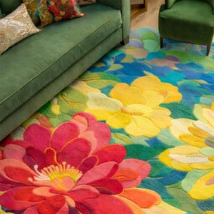 May include: A colorful floral rug with large, stylized flowers in shades of red, yellow, and blue. The rug is placed beneath a green sofa and armchair, creating a vibrant and inviting living space.