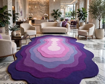 May include: An irregular, organic-shaped area rug featuring concentric, wavy layers of color transitioning from a light pink center to shades of lavender, violet, and deep purple. The text S.S. RUG CREATION is printed in the bottom left corner.