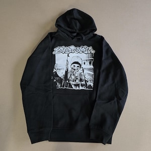 May include: Black hooded sweatshirt with a white graphic print of a person wearing a face mask and holding a rifle. The graphic also includes the word "Dystopia" in white.