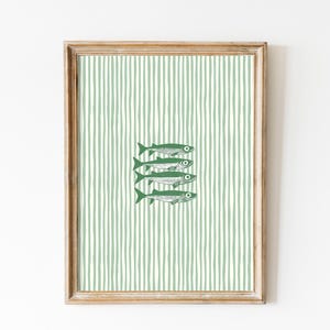 Könnte beinhalten: Gerahmter Kunstdruck mit grün-weiß gestreiftem Hintergrund und vier stilisierten grünen Fischen. Das Kunstwerk ist in einem Holzrahmen gefasst. Minimalistisches Design.