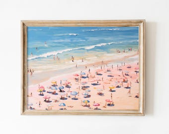 Op de afbeelding: Een ingelijst schilderij van een strandscène met mensen en kleurrijke parasols. Het schilderij toont een zandstrand met blauw water en een helderblauwe lucht.