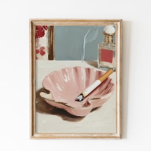 May include: A framed painting depicts a pink seashell ashtray with a lit cigarette, a perfume bottle, and a window scene. The artwork has a vintage aesthetic, with soft colors and a focus on still life elements.
