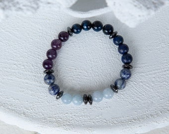 May include: A beaded bracelet with blue, purple, and light blue stones separated by silver beads.