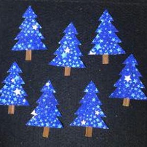 May include: Seven flat, triangular-shaped Christmas tree cutouts arranged in a cluster. Each tree features a vibrant blue background patterned with small, white, five-pointed stars and includes a small, rectangular brown trunk at the base.