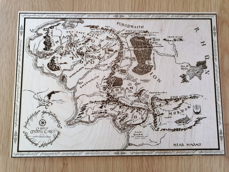 May include: A wood-burned map of Middle-earth from The Lord of the Rings. The map shows the major regions of Middle-earth, including Mordor, Rohan, and Gondor. The map is surrounded by a decorative border.
