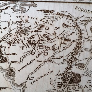 May include: A close-up of a wood-burned map of Middle-earth from The Lord of the Rings. The map shows the regions of Eriador, Lothl&oacute;rien, and Rohan. The text "FORODWAITH" is visible in the upper right corner.