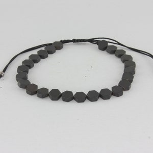 Könnte beinhalten: Ein schwarzes Armband mit sechseckigem Perlenmuster und verstellbarem Kordelverschluss.