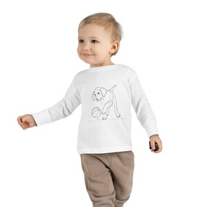 May include: White long-sleeve shirt with a black line drawing of a puppy playing with a ball.