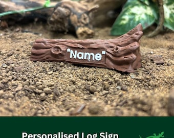 May include: A brown wooden log sign with the word "Name" printed in white letters. The sign is sitting on a bed of brown dirt.