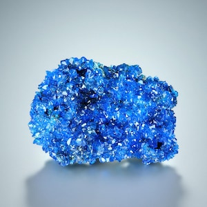 May include: A large cluster of vibrant blue crystals, showcasing a natural mineral formation. The crystals are densely packed together, creating a visually stunning display of color and texture.
